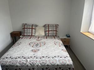 a bed with a white comforter with hearts on it at La petite maison in Plélan-le-Petit