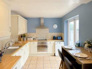 a kitchen with white cabinets and blue walls at The Yorkshire Hosts - Spokey Dokey House in Whixley
