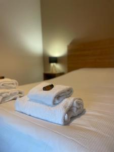 une pile de serviettes blanches assises sur un lit dans l'établissement KOSY Appart'Hôtel 7ème Art, à Saint-Avold