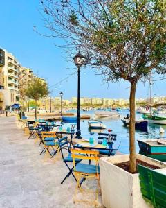 a row of tables and chairs with boats in the water at Luxury home with sea views in St. Julianʼs