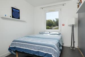 Bett in einem weißen Zimmer mit Fenster in der Unterkunft L Entre2mers in Sadirac
