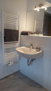 een badkamer met een witte wastafel en een spiegel bij Wohnung Nr 4 in Bargischow