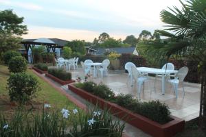 a row of white tables and chairs in a garden at Thokoza guest house in Manzini