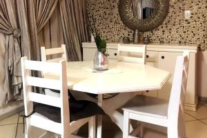 - une table à manger blanche avec des chaises et un miroir dans l'établissement Modern style Apartment in Pretoria-Central, à Pretoria
