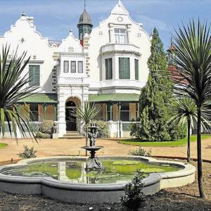 a large white house with a fountain in front of it at Modern style Apartment in Pretoria-Central in Pretoria