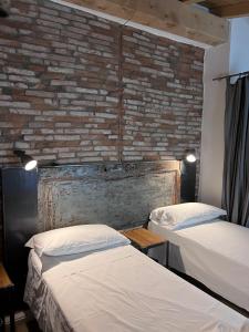 Borgovivo Il tuo Loft in centro città في بيرغامو: سريرين في غرفة مع جدار من الطوب