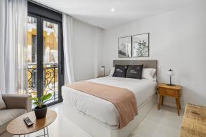 - une chambre blanche avec un lit et un canapé dans l'établissement limehome Madrid Calle de la Paloma, à Madrid
