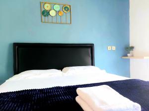 a bed with a black headboard and two towels on it at FHStay Malioboro in Timuran