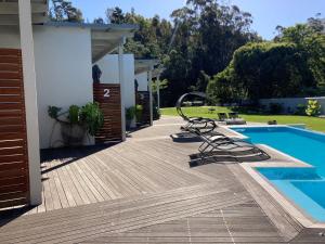 a deck with a pool and chairs next to a house at A Riverbed Guesthouse in Swellendam