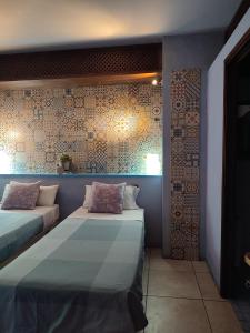 een kamer met 2 bedden en een muur met tegels bij HOTEL PASTERAL RIU TER in La Cellera de Ter
