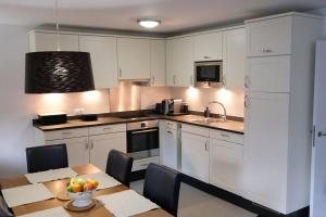 a kitchen with white cabinets and a table with a bowl of fruit at Wonderful holiday home on the shore of Walensee in Quarten