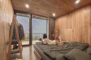a person laying on a bed in a room with a window at Lù Homestay Tà Xùa in Bắc Yên