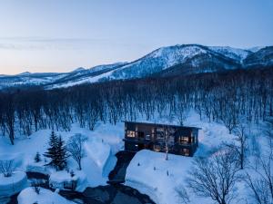 a house in the snow with mountains in the background at Song Saa Chalet in Niseko