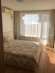 a bedroom with a bed and a large window at Квартира у моря in Sveti Vlas