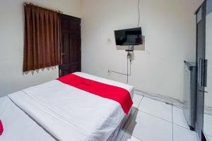una camera con un letto con una coperta rossa e bianca di RedDoorz At Graha 99 Simomulyo a Surabaya