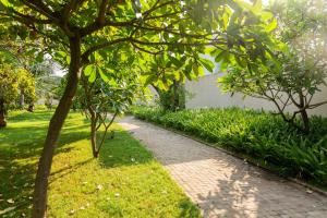 a brick path in a park with trees and grass at Bella Norma with Pool - North Goa at StayVista in Calangute