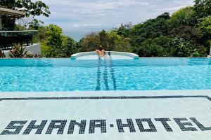 a person is standing on the edge of a swimming pool at Shana by the Beach Manuel Antonio in Manuel Antonio