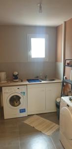 uma cozinha com uma máquina de lavar roupa e um lavatório em la boufanelle em Montséret