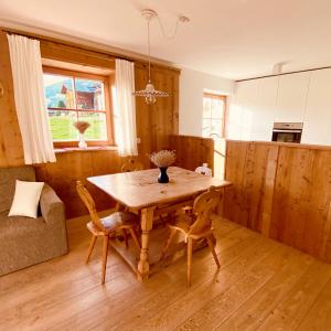 uma cozinha com uma mesa de madeira e cadeiras num quarto em Le Crode em Sesto