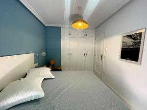 1 dormitorio con cama y pared azul en Apartamento La Peatonal, en Hervás