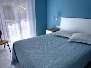 a blue bedroom with a bed and a window at Apartamento La Peatonal in Hervás