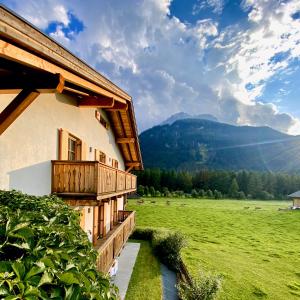 a building with a balcony with a field and mountains at Le Crode in Sesto