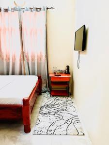 um quarto com uma cama e uma mesa com uma televisão em Nakupenda em Mazizini