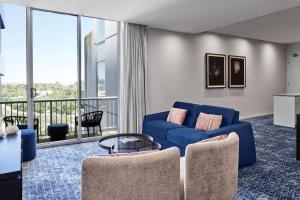 a living room with a blue couch and a balcony at Adina Apartment Hotel Melbourne Flinders Street in Melbourne