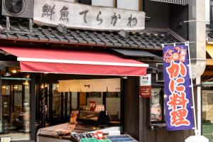 uma frente de loja com um toldo vermelho num edifício em 一日一組の隠れ宿　てらかわ em Kinosaki