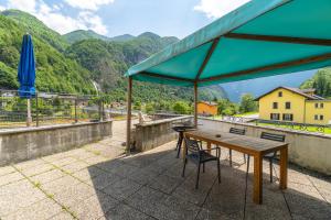 a table and chairs on a roof with a view of mountains at Lizard House in Cevio