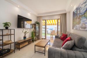 soggiorno con divano grigio e cuscini rossi di MAapartmentsES Garden City a Playa Fañabe