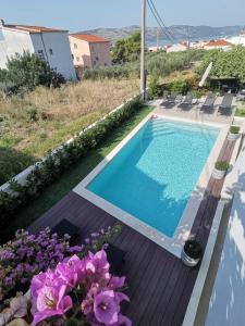 a swimming pool in a yard with purple flowers at Paulina Harmony Rooms in Seget Vranjica