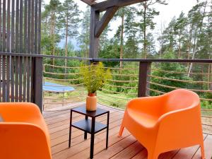 a porch with orange chairs and a table with a plant at Polana Gawrycha, domki nad jeziorem z widokiem in Suwałki