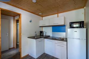 a kitchen with white cabinets and a refrigerator at Village Vacances Passion La Bayette in Le Pradet