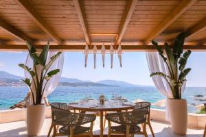 a dining room with a table and chairs and the ocean at Hôtel Marinca & Spa in Olmeto