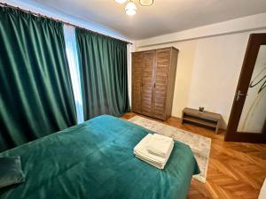 a bedroom with a green bed and green curtains at Stella's cozy home in Baloteşti