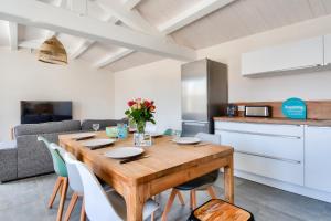 eine Küche und ein Esszimmer mit einem Holztisch und Stühlen in der Unterkunft Echapee familiale a l Epine in LʼÉpine