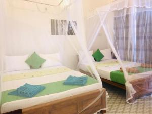two beds in a room with mosquito nets at Darshani Lodge in Sigiriya