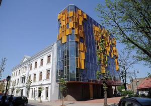 wysoki szklany budynek z żółtymi oknami na ulicy w obiekcie Cēsu apartamenti w mieście Kieś