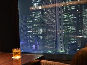 a drink on a table in a bar with a view of a city at Shinjuku Prince Hotel in Tokyo