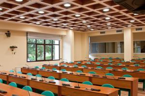 an empty lecture hall with wooden tables and blue chairs at Villa Lomellini in Montebello della Battaglia