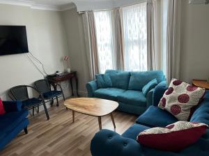 a living room with a blue couch and a table at Relaxing home - 7-10min to Bournemouth sandy beach by car - private garden, parking and spa in Bournemouth