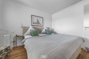 a white bedroom with a large bed with green pillows at Segler Nest in Olpenitz
