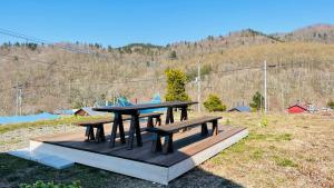 a picnic table and benches in a field at NORD 3 自然豊かな家 - Manji Village - in Iwamizawa