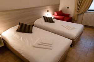 2 Betten in einem Hotelzimmer mit einem roten Stuhl in der Unterkunft Villa Lomellini in Montebello della Battaglia