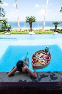 a little girl laying next to a pool with a tray of food at Cliff Front pandawa Beach Karang Kembar 5 in Ungasan