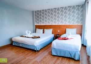 2 camas en una habitación de hotel con sábanas blancas en CBD Hotel Suratthani, en Suratthani