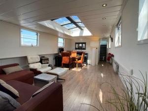 a living room with a skylight and a room with a table at Spacious homely house boat in Amsterdam