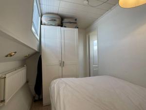 Spacious homely house boat في أمستردام: غرفة نوم صغيرة بها سرير ودواليب بيضاء