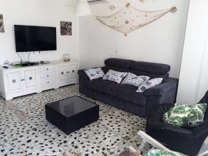 sala de estar con sofá y TV de pantalla plana en Tranquila casa frente al mar, en Adra